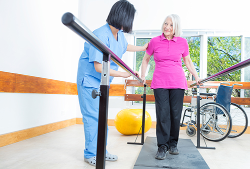 Nurse assisting elderly woman with physical therapy